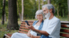 Älteres Paar auf Bank im Wald mit Handy
