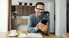 Mann sitzt mit Handy in seinem Zuhause