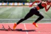 Läuferin startet aus Startblock auf einer Tartanbahn