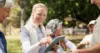 Frau leitet Sportgruppe draussen mit iPad an