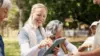 Frau leitet Sportgruppe draussen mit iPad an